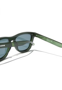 Vihreät muoviset aurinkolasit tummilla linsseillä, pyöreäkehysmuotoilu ja ohuet vihreät sankalistat, joissa on kohokuvioitu brändäys.