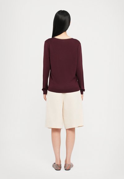 Burgunderfarbenes Langarmoberteil, cremefarbene Shorts und mehrfarbige Ballerinas. Glatter Stoff, lockere Passform und knielange Shorts. Minimalistisches Design.