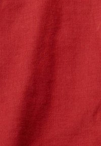 Tissu rouge à côtes avec une texture lisse. Les lignes verticales créent un motif régulier sur toute la surface du matériau.