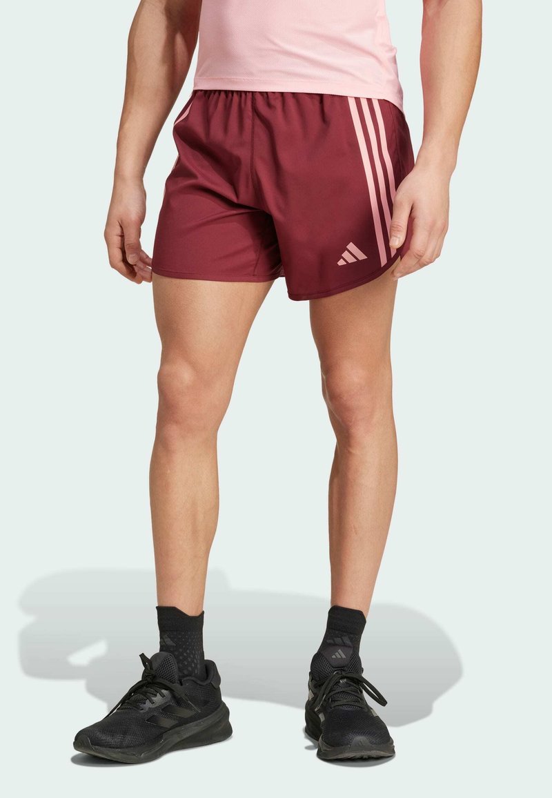 Bordowe szorty sportowe z różowymi paskami po bokach, wykonane z lekkiego materiału. Stylizowane z marszczonym elastycznym pasem i detalem z logo.