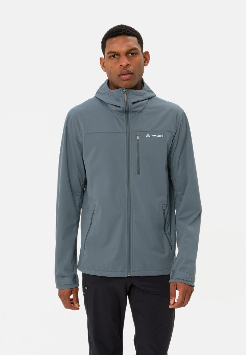 Veste softshell grise avec capuche, fermeture éclair frontale et deux poches latérales zippées. Présente un logo sur la partie gauche de la poitrine. Texture lisse.