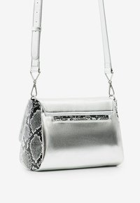 Srebrna metaliczna torebka na ramię z fakturowanym czarno-białym wzorem przypominającym skórę węża. Posiada płaską klapę i regulowany pasek.