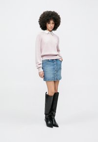 Gaiši rozā ribota džemperis ar baltu apkakli, kombinēts ar gaiši zilu džinsa svārku ar pogu detaļām. Melni ceļgalu augstie, smailu purngalu zābaki.