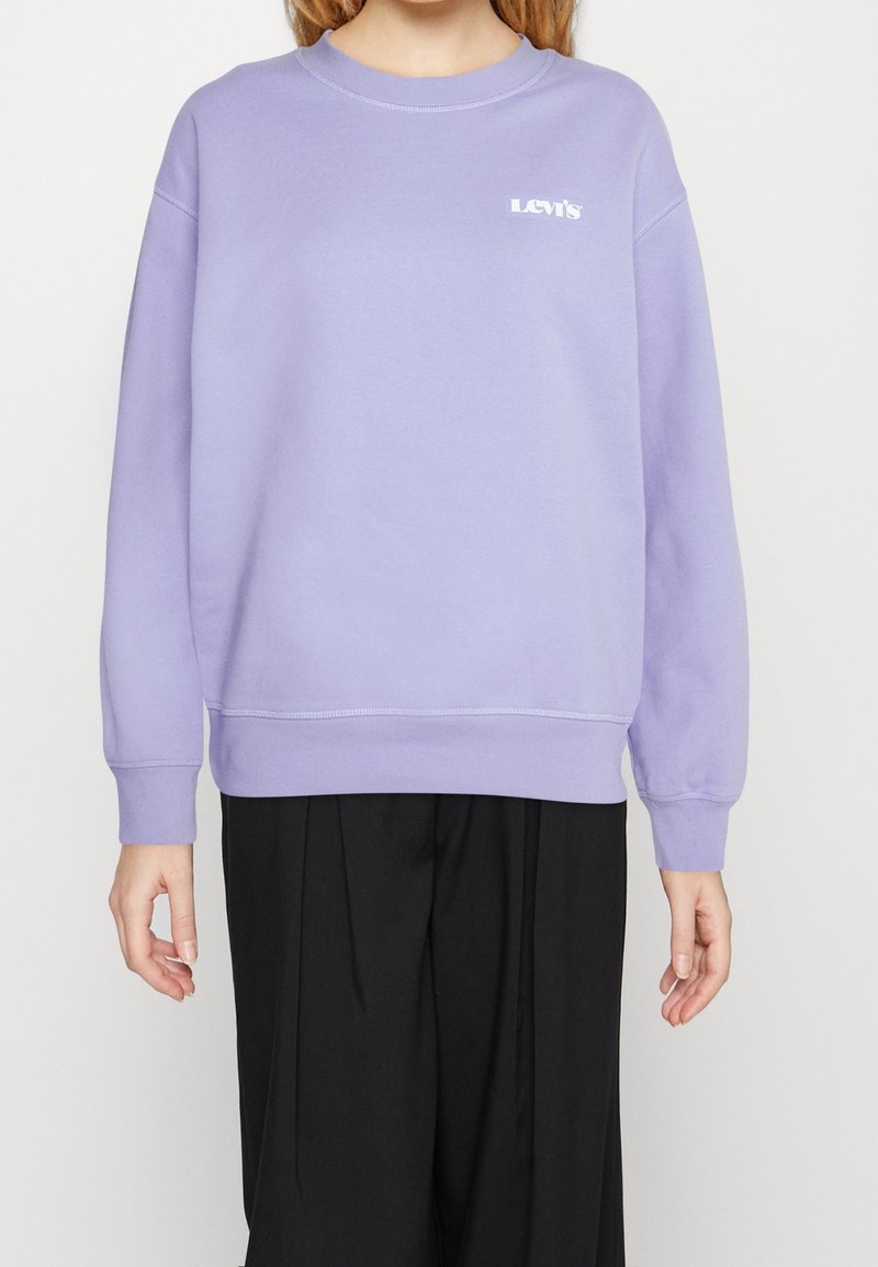 Sudadera de color púrpura claro con escote redondo y puños acanalados. Presenta un pequeño logotipo blanco de Levi's en el pecho. Material suave, ajuste relajado.