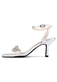 Silver high-heel sandal with a transparent strap and decorative rhinestone accents. Features a rounded toe and a slim ankle strap.