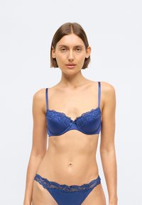 Σέτ εσώρουχων σε βασιλικό μπλε χρώμα που περιλαμβάνει ένα μαξιλαρωμένο σουτιέν με δαντελένιες λεπτομέρειες και αντίστοιχο σλιπ. Λείο σατέν υλικό και ρυθμιζόμενοι ιμάντες.