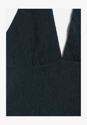 Sort tekstureret stofkjole med dyb V-udskæring og rynkedetalje ved brystet, set i nærbillede af den øverste forreste del.