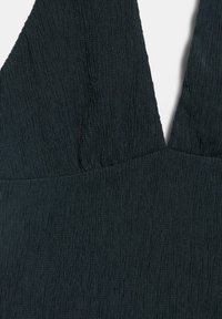 Robe en tissu noir texturé avec un décolleté en V profond et un détail froncé au niveau de la poitrine, montrant un gros plan de la partie supérieure avant.