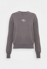 Felpa grigia in cotone con maniche lunghe, collo rotondo, polsini e orlo a costine. Presenta un logo bianco "Calvin Klein Jeans" sul petto.