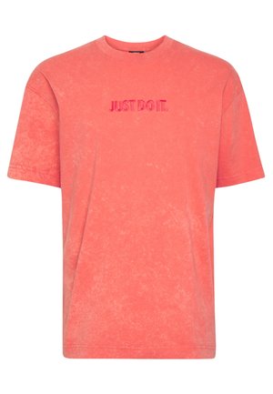 Jasnoróżowa (koralowa) koszulka z krótkim rękawem, z okrągłym dekoltem i "JUST DO IT." wyhaftowanym na czerwono na piersi.