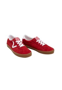 Sneakers in suede rosso con lacci e linguetta bianchi, dotati di una suola in gomma marrone e di un'etichetta con logo sulla linguetta. Design con punta arrotondata.