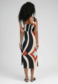 Robe maxi avec un motif géométrique coloré en noir, crème, rouge et bleu. Dotée de bretelles réglables et d'un détail dos smocké.