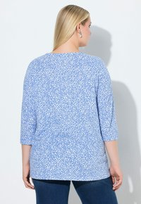 Blauw-wit T-shirt met korte mouwen en een verspreid bloemenpatroon, zachte stof, losse pasvorm en een ronde hals, gecombineerd met een donker denim jeans.