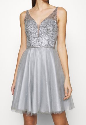 Abito da cocktail senza maniche in argento con scollatura a V profonda, corpetto aderente ricoperto di paillettes e gonna a linea A in tulle scintillante che termina sopra le ginocchia.