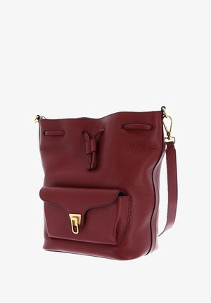 Borsa a secchiello in pelle rossa con superficie testurizzata, presenta una tasca frontale con finiture in oro e una tracolla rimovibile.