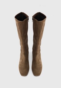 Bottes hautes en daim marron au-dessus du genou, avec un bout carré et des fermetures éclair sur les côtés intérieurs, présentant une texture douce et une silhouette lisse.