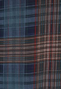Woven tartan fabric featuring blue, green, brown, and red lines in various check patterns; soft texture with a blend of colors.