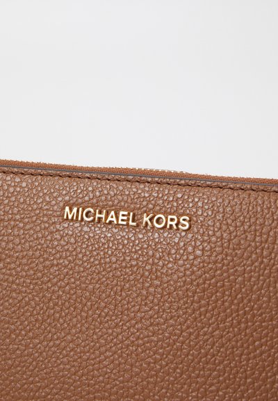 Portefeuille en cuir texturé marron avec un logo doré "MICHAEL KORS". La fermeture éclair est dotée d'une bordure lisse pour un verrouillage facile.