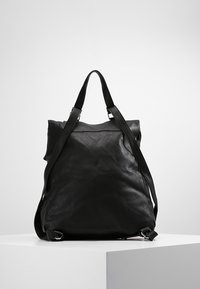 Černý kožený batoh s texturovaným povrchem, dvěma nastavovacími popruhy a překlápěcím vrškem zajištěným stříbrným kováním.