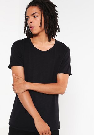 Camiseta de algodón negra con escote redondo, mangas cortas y un corte relajado. Textura suave sin patrones visibles ni herrajes.