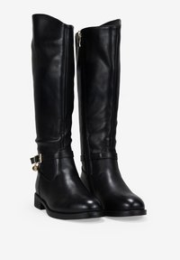 Botas de cuero negras hasta la rodilla con una textura suave, cierre de cremallera lateral y una correa decorativa con un detalle en dorado.