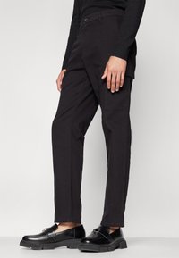 Pantalones cargo negros hechos de una tela duradera, con corte recto, bolsillos laterales y cierre de botón para un ajuste seguro.