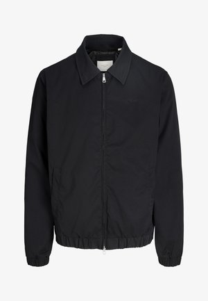 Schwarze Reißverschlussjacke mit Kragen, elastischen Bündchen und Saum sowie einem dezenten Logo auf der linken Brust, dargestellt vor einem weißen Hintergrund.