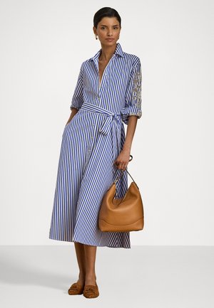 Rochie cambrată cu dungi albastre și albe, cu cravată la talie, mâneci 3/4 și accente din dantelă. Asortată cu o geantă din piele deschisă la culoare și încălțăminte maro.