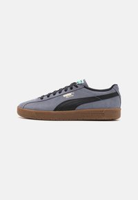 Puma Delphin sneakers in grey suede with black accents, lace-up design, and gum rubber outsole. Features logo on the side and tongue.