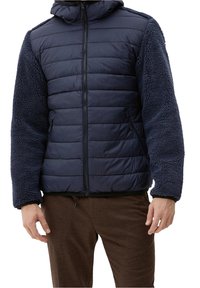 Giacca blu navy con parte anteriore trapuntata e imbottita e maniche in tessuto morbido e textured. Presenta un cappuccio e tasche con zip. Materiale morbido.