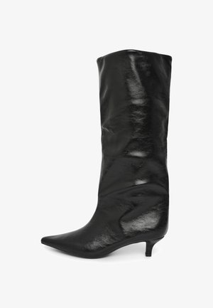 Schwarze, spitz zulaufende Knöchelstiefel aus glattem Leder mit einer schlanken, niedrigen Absatzhöhe und einem lässigen Design, das die Wade bedeckt.