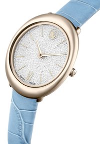 Orologio rotondo con quadrante glitter argento, indici delle ore dorati e cinturino in pelle con motivo coccodrillo azzurro chiaro. Realizzato in Svizzera, design elegante.