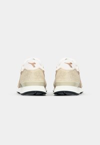 Beige suede and white nylon running shoes with subtle pink accents and a black rubber sole. Features a padded collar and logo on heel.