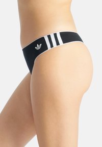 Czarny bikini z białym wzorem w trzy paski na pasku, z małym logo. Materiał wydaje się gładki i elastyczny, z niskim stanem.