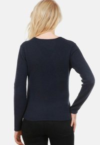 Pull bleu marine à manches longues en tissu tricoté doux, doté d'un col rond et d'un ourlet subtil, conçu pour offrir une silhouette ajustée.