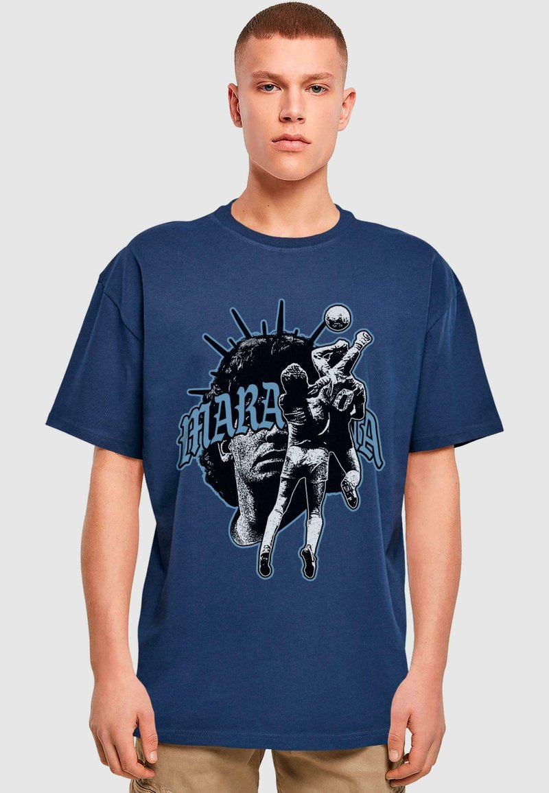 Marineblå bomulds T-shirt med grafisk tryk af en spiller og et ansigt, med fed skrift i blå og sort. Løs pasform, rund hals design.
