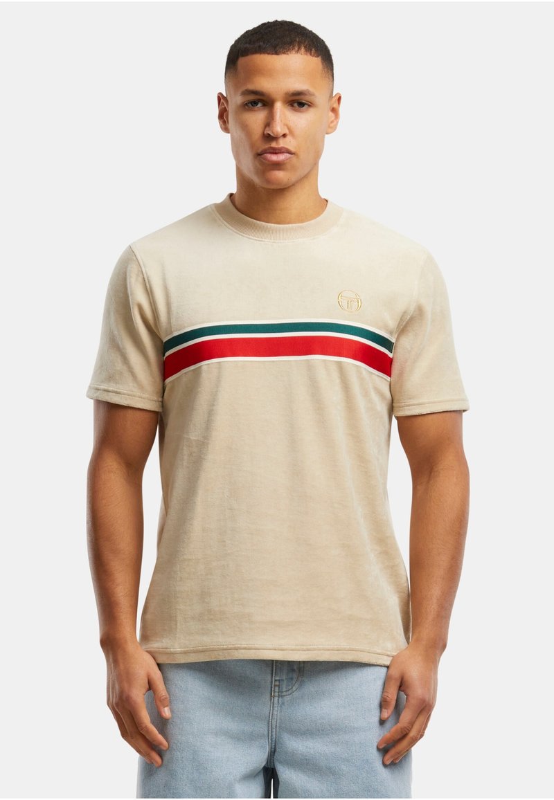 Camiseta beige de manga corta, con un diseño de rayas horizontales en rojo, verde y azul a lo largo del pecho. Pequeño logo en el lado izquierdo.