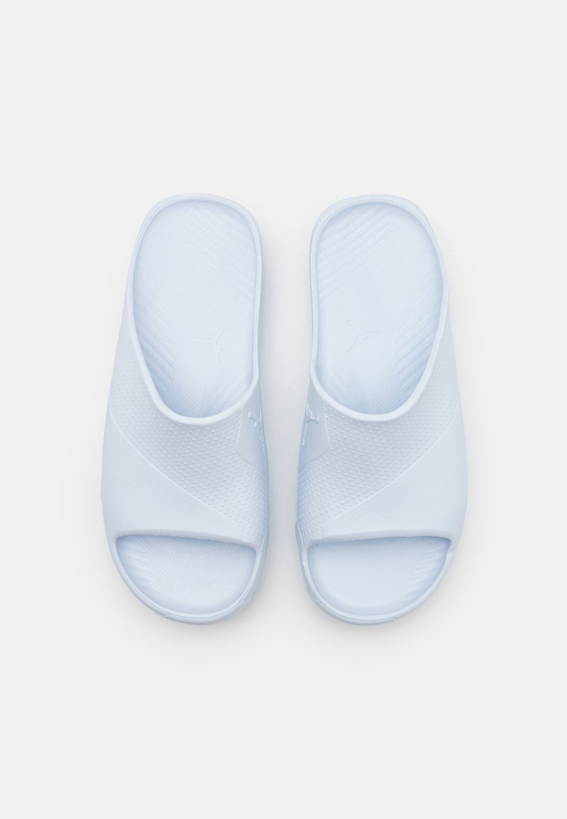 Une paire de sandales en caoutchouc ouvertes aux orteils, de couleur bleu clair, avec des semelles intérieures texturées et un motif perforé subtil sur le dessus.