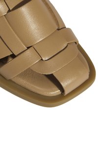 Gewebte sandfarbene Leder-Sandale mit eckiger Zehenpartie, gepolsterter Innensohle und glatter Oberfläche mit einem subtilen Glanz sowie Gummisohle.