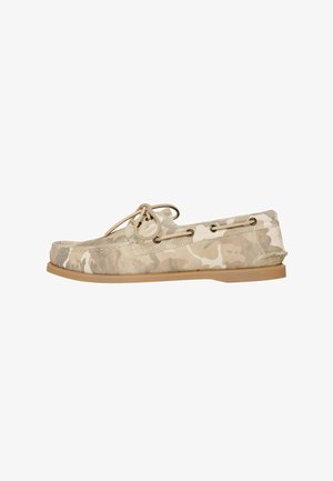 Beige og creme camo-mønstret mokkasin loafer med tan gummisål og snore af læder på siden og toppen.