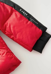 Czerwona kurtka ocieplana z czarnym kołnierzem i mankietami. Posiada logo marki "BAKER by TED BAKER" w białym tekście na kołnierzu. Gładka, błyszcząca tekstura.