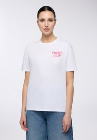 T-shirt bianca in cotone con una grafica rosa "FRESH UP" nella parte sinistra del petto, dal taglio rilassato e maniche corte.