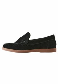 Mocassins en cuir suédé noir avec une texture douce, dotés d'un dessus cousu et d'une semelle en caoutchouc brun flexible. Conçus avec un profil élancé et un petit empeigne.