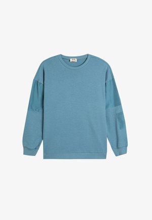 Helles blaues Sweatshirt aus weichem Baumwollstoff, mit rundem Halsauschnitt, langen Ärmeln mit unterschiedlichen Texturen und einer aufgesetzten Tasche am linken Arm.