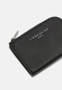 Czarny portfel ze skóry o fakturowanej powierzchni, z zamkiem błyskawicznym i srebrnym logo. Kompaktowy i prostokątny kształt.