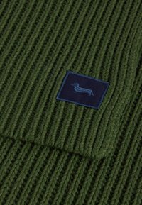 Groene ribbel tricot stof met een marineblauw rechthoekig stuk waarin een honden silhouet in een lichtere blauwe kleur is geborduurd.