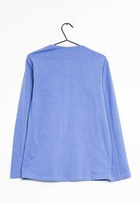 Pitkähihaista vaaleansinistä paitaa, joka on valmistettu pehmeästä puuvillasta, jossa on pyöreä kaula-aukko ja suora helma, esillä mustalla ripustimella.