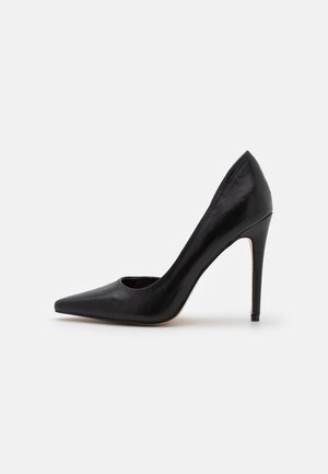 Zwarte leren high-heeled pump met een spitse neus en uitsnijdingen. Ondanks de stiletto-hak voor verhoging, heeft het een gladde textuur.