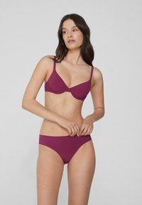 Mauve-Bikini-Set mit einem glatten, dehnbaren Stoff. Der BH hat einen tiefen Ausschnitt und verstellbare Träger; der Slip ist im klassischen Brief-Stil.