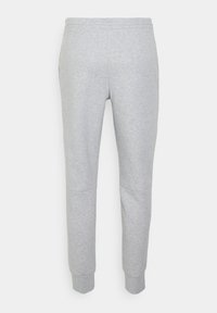 Pantaloni de trening gri, confecționați dintr-un material moale, cu un design conic, manșete ribbate și detalii cu panouri la genunchi pentru o structură suplimentară.